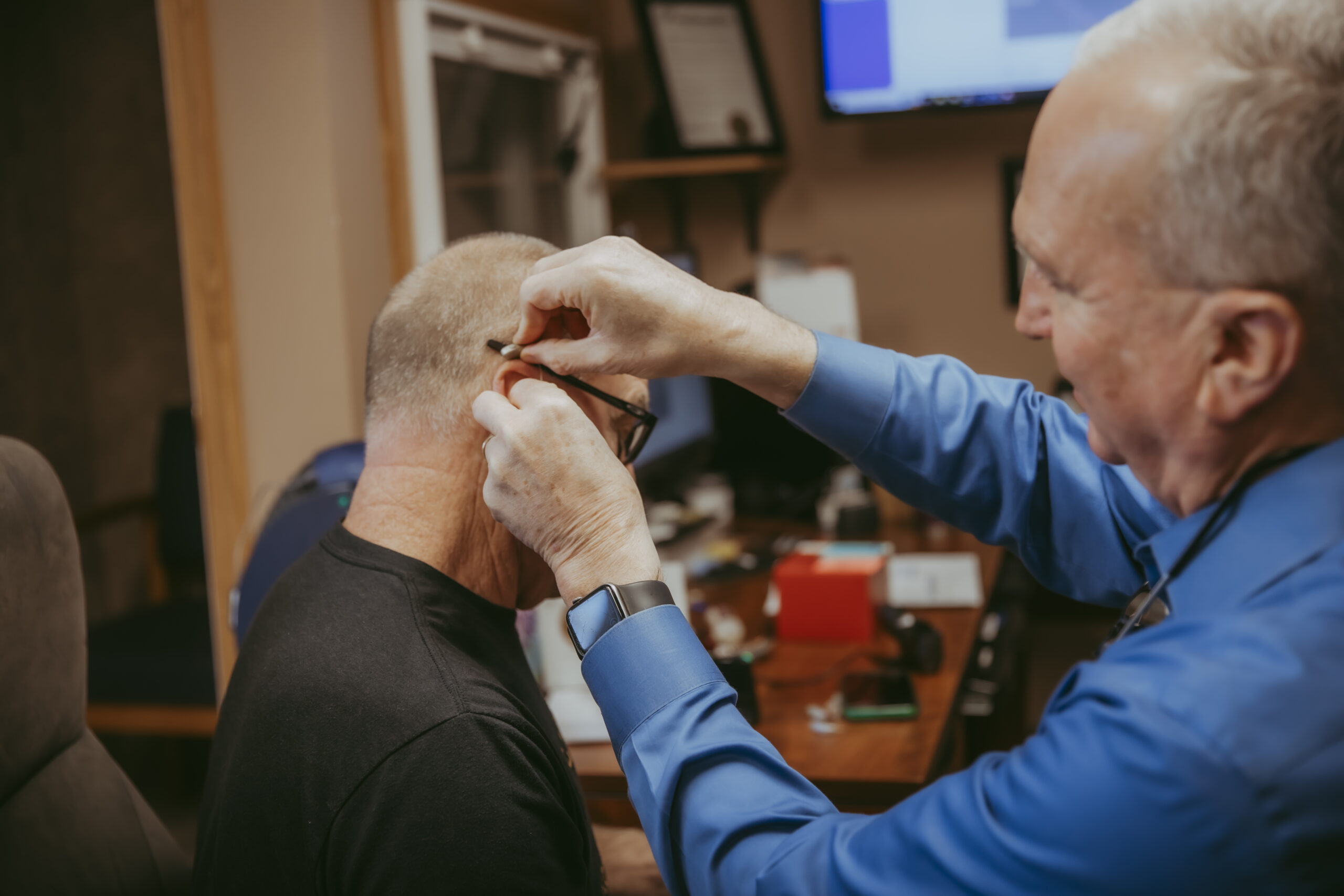 Dave adjusts patients hearing aid