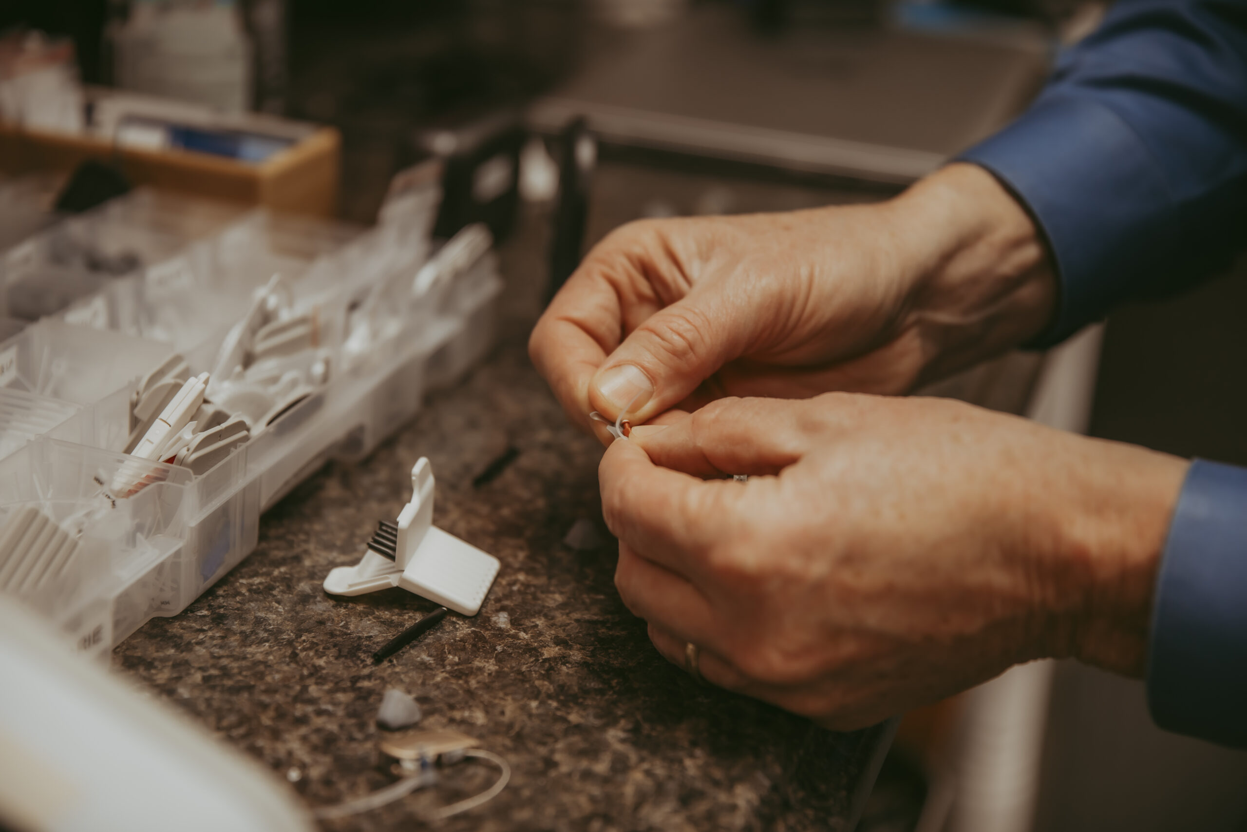 An audiologist repairs hearing aids